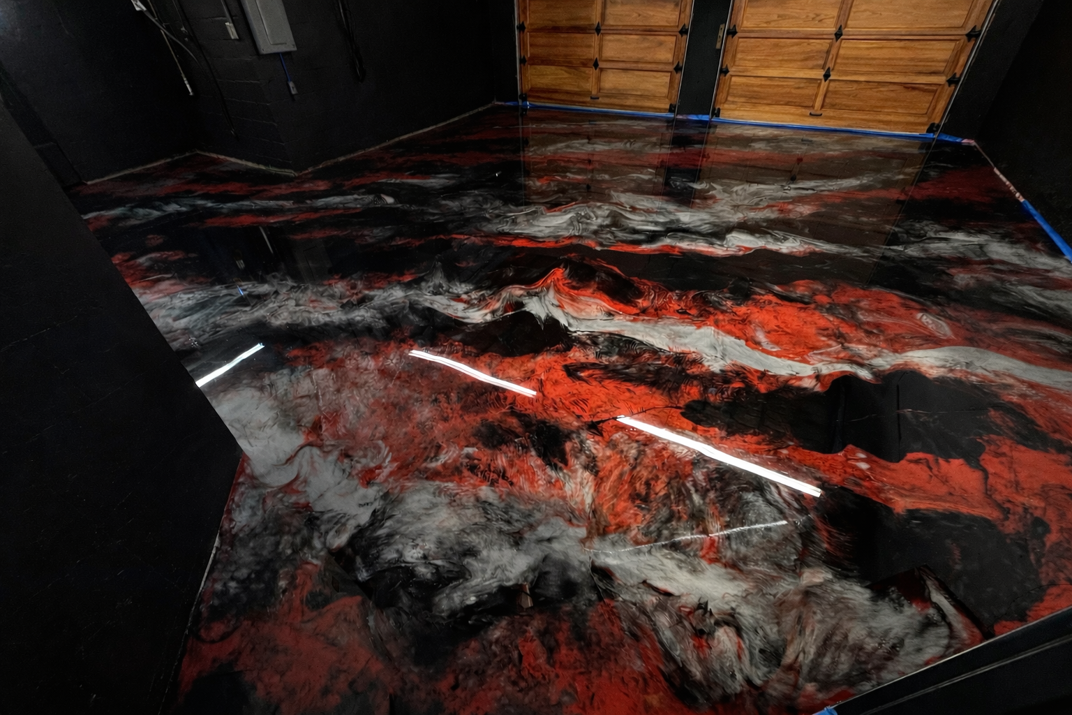 Red and black metallic epoxy garage floor with a sports car