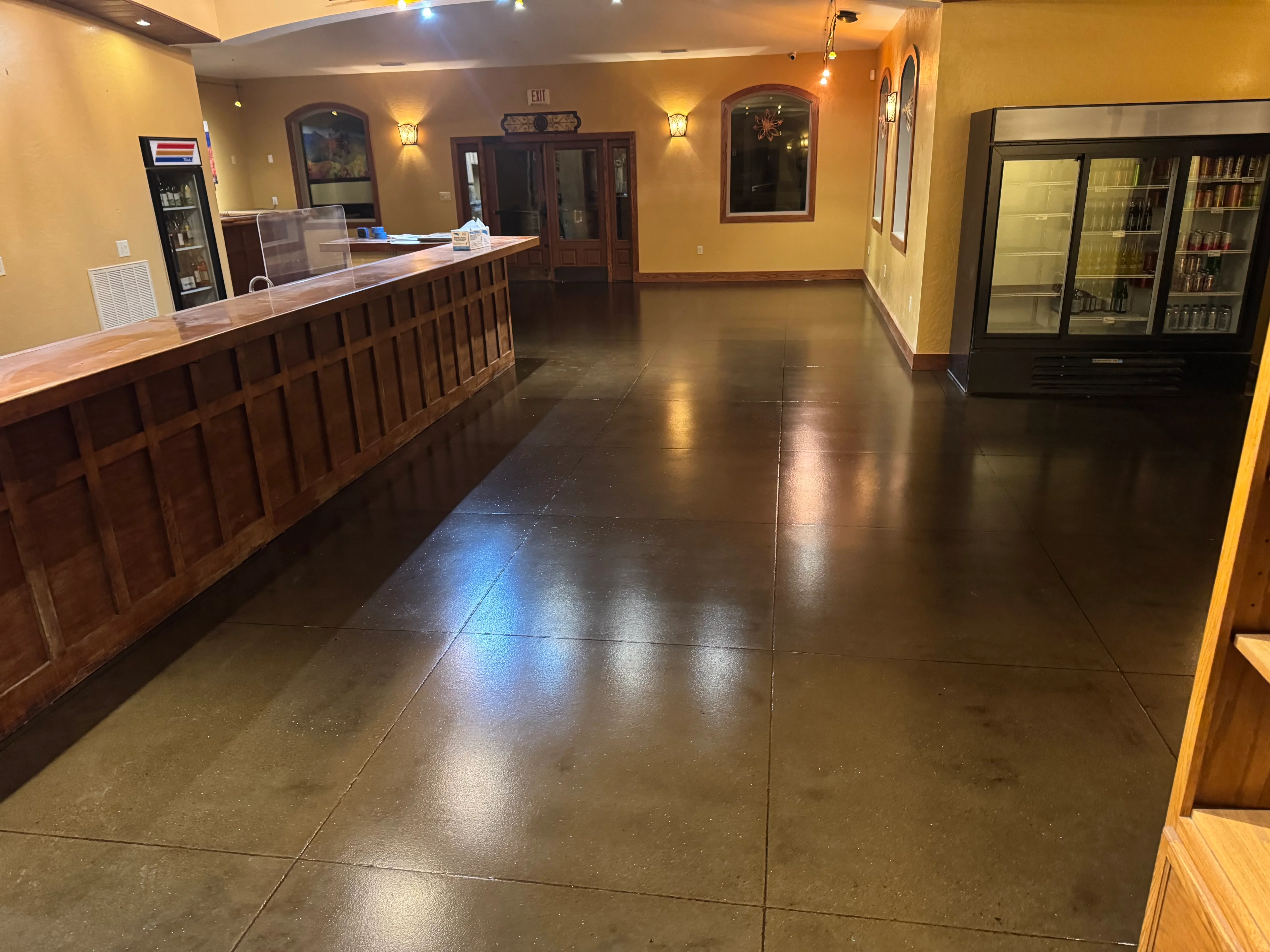 Dark epoxy-coated concrete floor in commercial retail space with wood counter and yellow walls