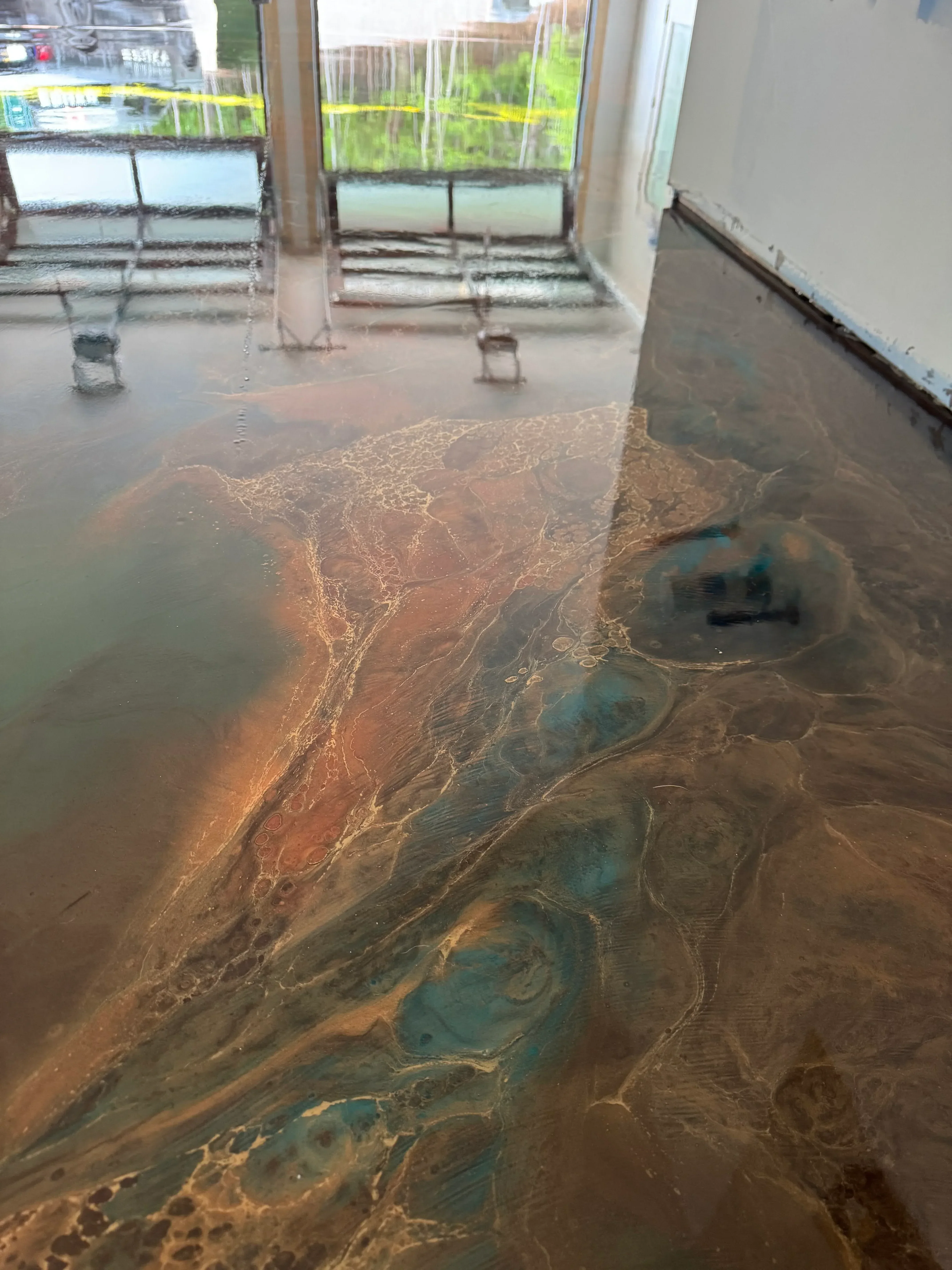 Metallic epoxy floor with teal and copper swirled pattern, concrete contractor work