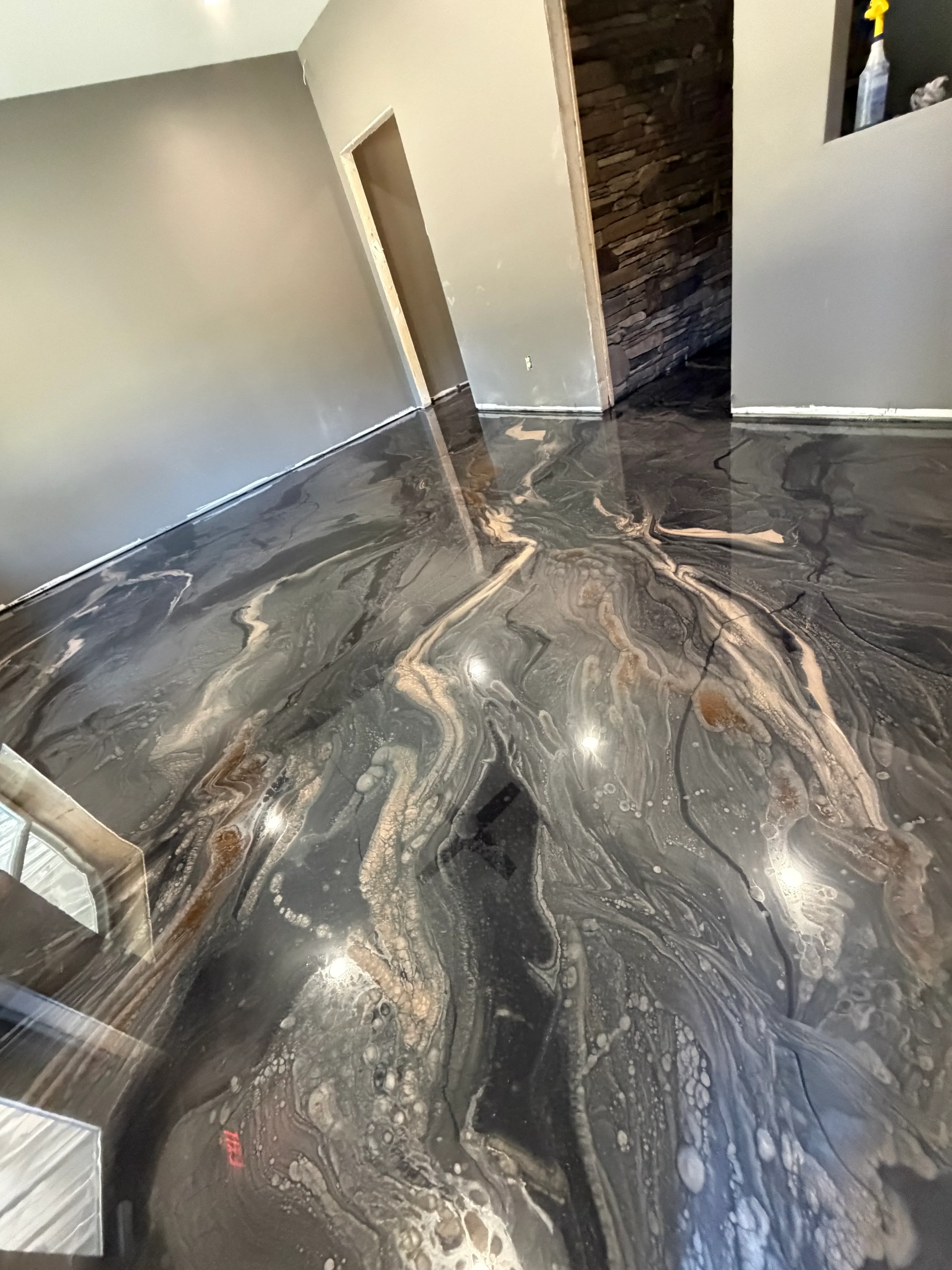 Metallic epoxy floor with charcoal and silver swirled patterns and high-gloss finish
