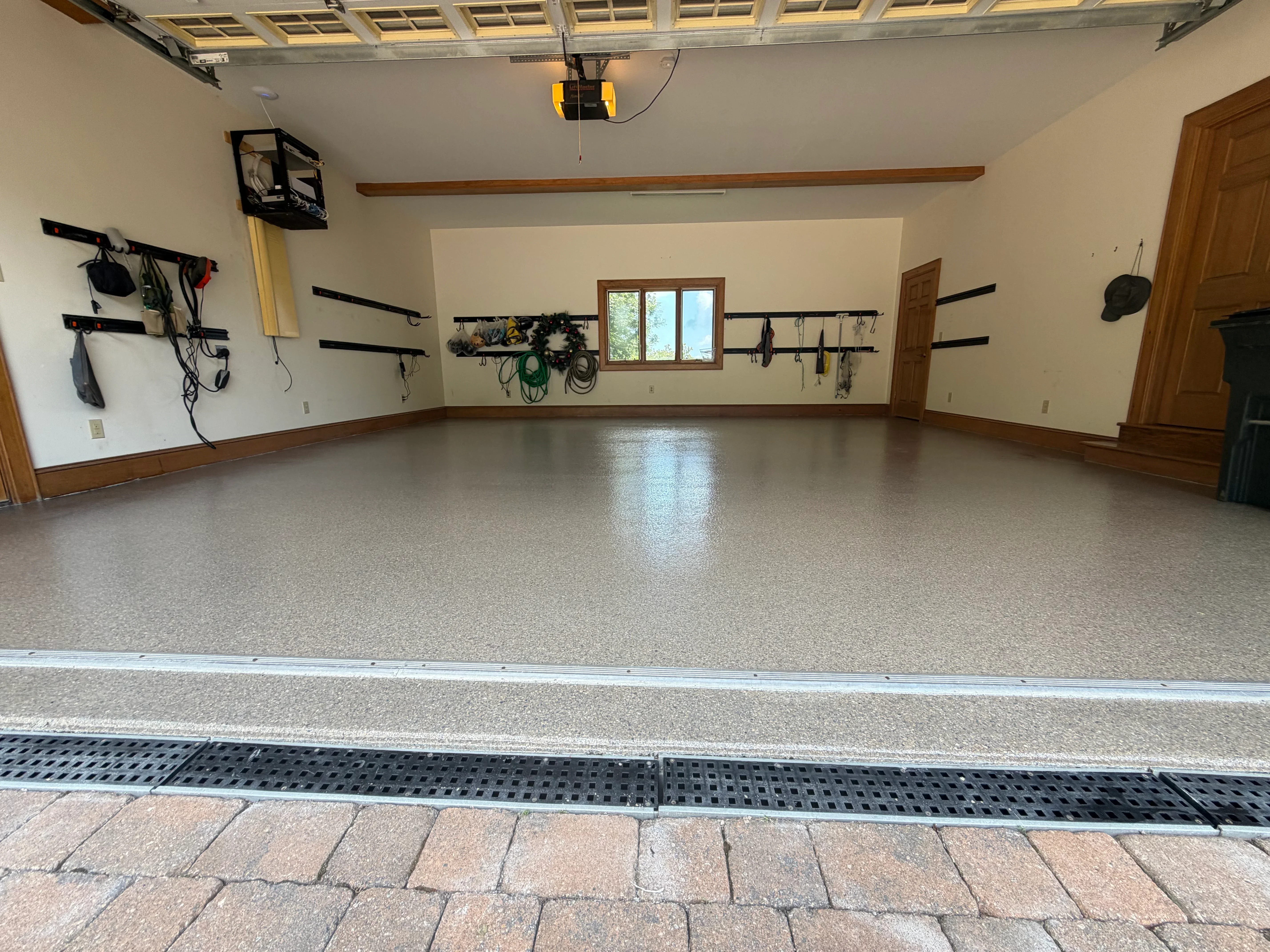Polished epoxy garage floor with glossy finish, wood trim, and wall-mounted storage systems