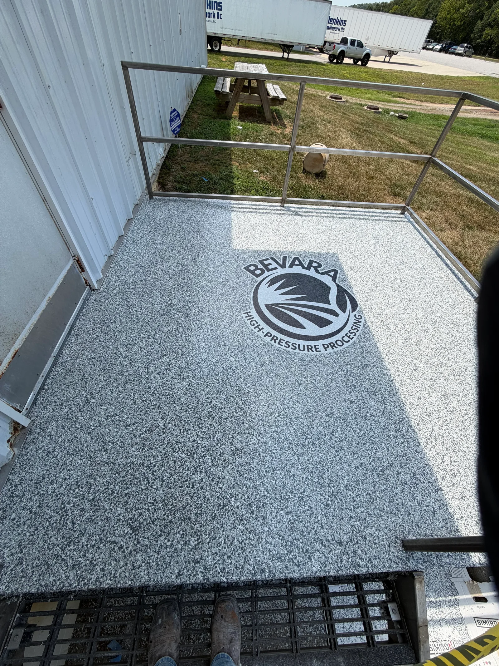 A freshly installed concrete patio floor behind a mountain home in Boone, NC, showing a smooth broom-finished surface with clean edges and a graded slope away from the foundation. The surrounding High Country landscape and tree line are visible in the background.