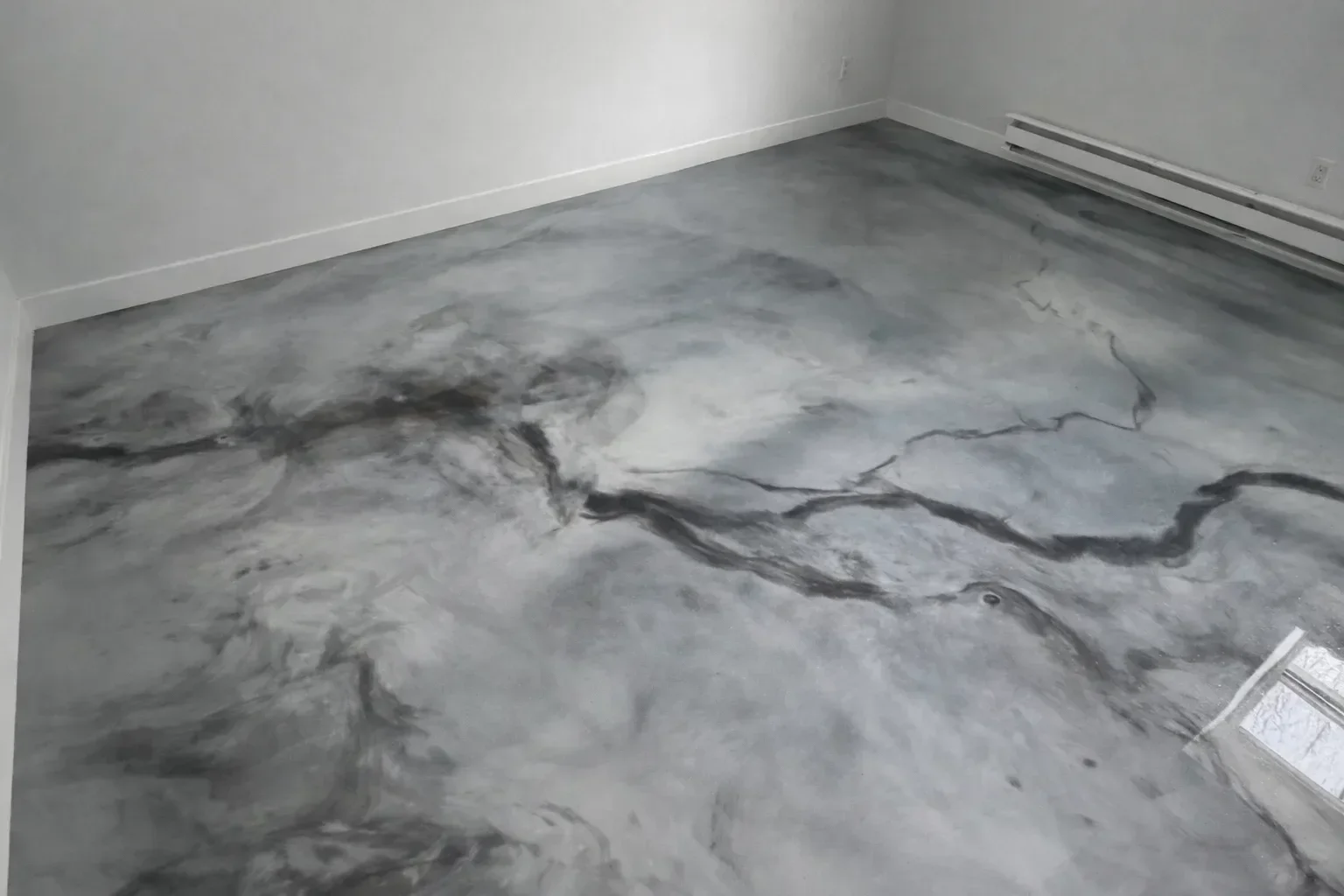 A high-gloss metallic epoxy floor with deep swirling bronze and charcoal tones installed in a residential garage in Boone, NC. The reflective surface shows the three-dimensional flowing pattern created during application.