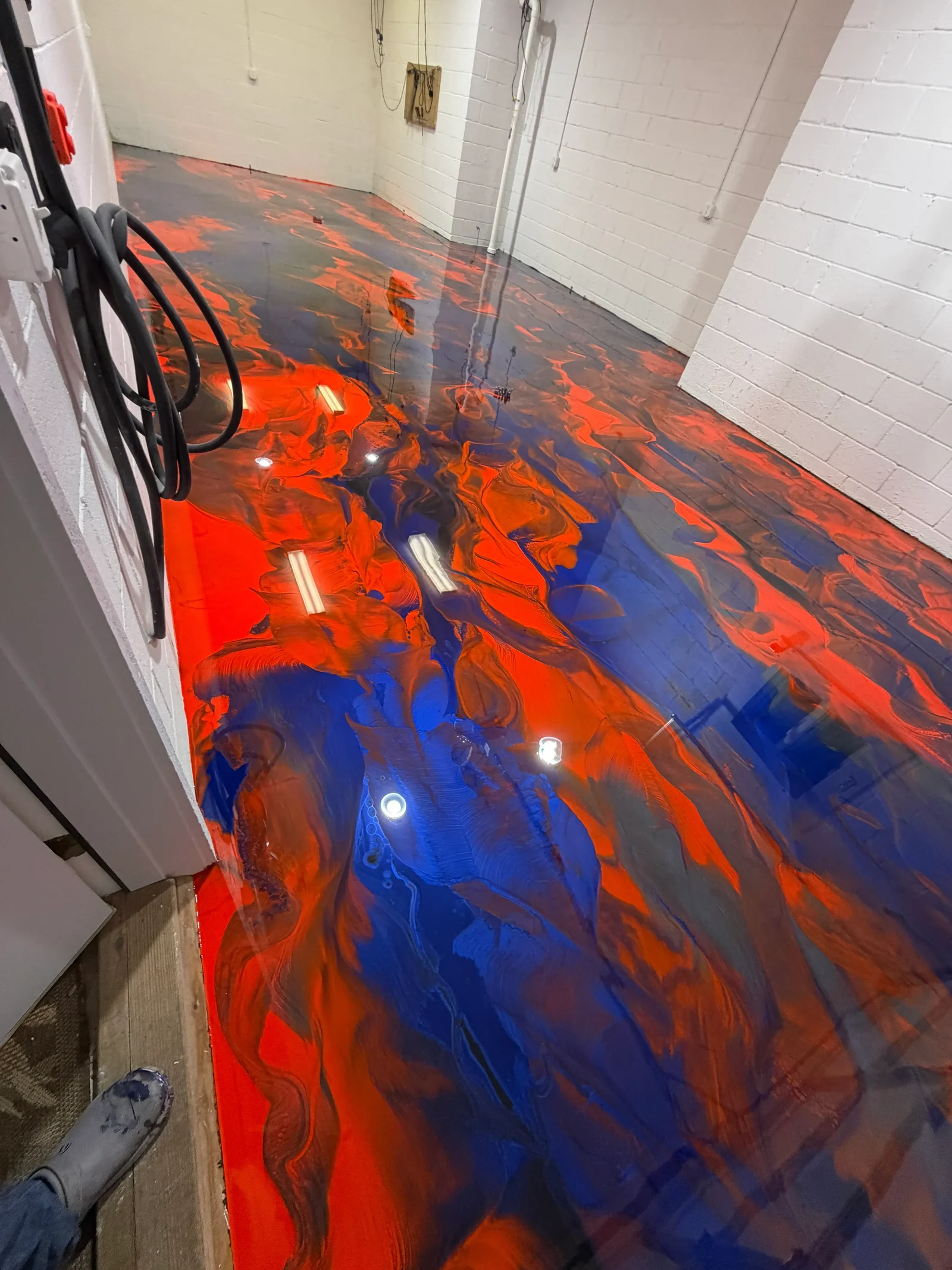 Finished metallic epoxy floor in a Boone, NC interior space showing a high-gloss swirled finish with deep color and light reflection. The seamless surface covers the full concrete slab with no visible joints or seams.