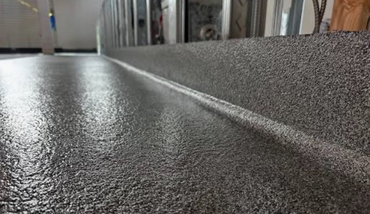 Close-up of textured gray quartz epoxy flooring with cove base